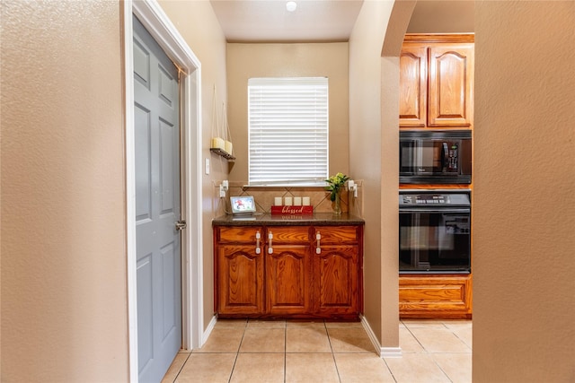 6500 Fannin Farm Way, Arlington, TX 76001 - kitchen with black appliances, light tile patterned floors, arched walkways, a textured wall, and brown cabinetry