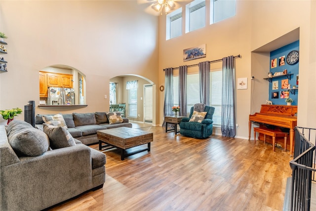 6500 Fannin Farm Way, Arlington, TX 76001 - living area featuring arched walkways, ceiling fan, a high ceiling, healthy amount of natural light, and light wood-style flooring