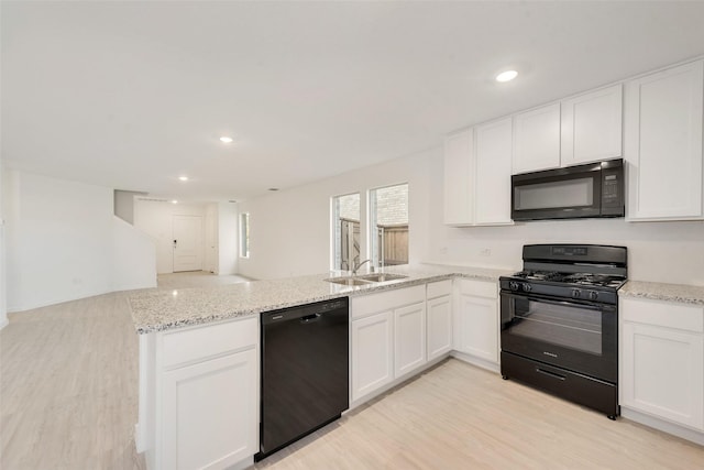4213 Brindley Rd, Little Elm, TX 75068 - kitchen with black appliances, a peninsula, light wood finished floors, white cabinets, and a sink