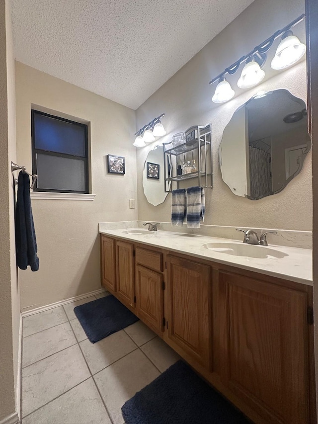7568 Casburn Ct, Fort Worth, TX 76120 - bathroom with a textured ceiling, tile patterned floors, double vanity, and baseboards