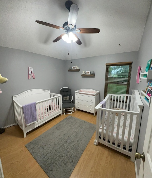 7568 Casburn Ct, Fort Worth, TX 76120 - bedroom with wood finished floors, ceiling fan, a textured ceiling, and a nursery area