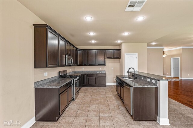 9214 Mykanos Trl, Shreveport, LA 71106 - kitchen with appliances with stainless steel finishes, a sink, baseboards, dark brown cabinets, and dark stone counters
