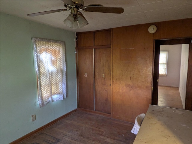 2214 N Woodland St, Amarillo, TX 79107 - unfurnished bedroom featuring wood finished floors, baseboards, a closet, a ceiling fan, and wooden walls