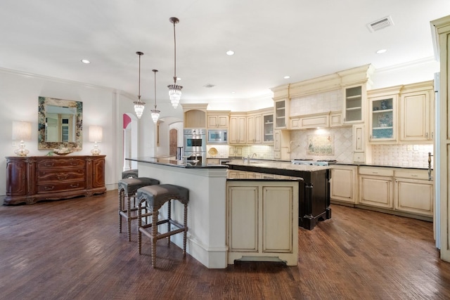 2306 Autumn Run Ct, Cedar Hill, TX 75104 - kitchen featuring cream cabinetry, appliances with stainless steel finishes, a large island, a breakfast bar, and crown molding