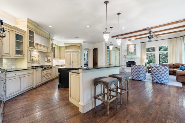 2306 Autumn Run Ct, Cedar Hill, TX 75104 - kitchen with cream cabinetry, an island with sink, open floor plan, stainless steel gas stovetop, and dark countertops