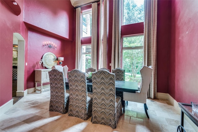 2306 Autumn Run Ct, Cedar Hill, TX 75104 - dining room featuring arched walkways, baseboards, stone tile flooring, and a high ceiling
