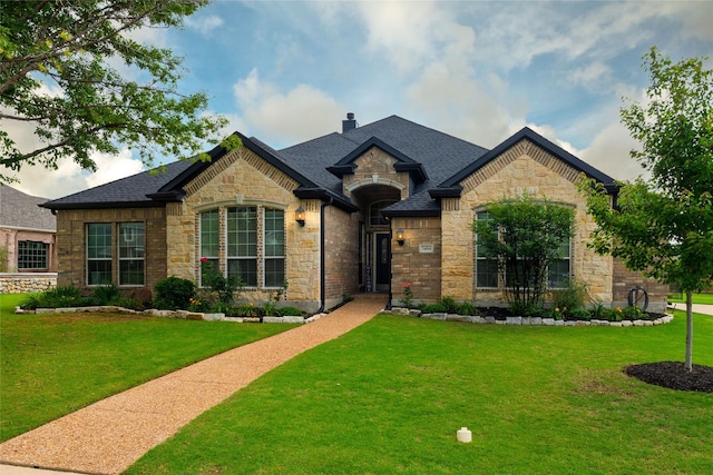 3404 Brookshire Run, Corinth, TX 76210 - french country home with stone siding, a front yard, a chimney, and a shingled roof