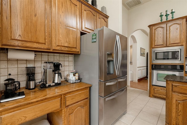 3404 Brookshire Run, Corinth, TX 76210 - kitchen with stainless steel appliances, tasteful backsplash, light tile patterned floors, and brown cabinetry