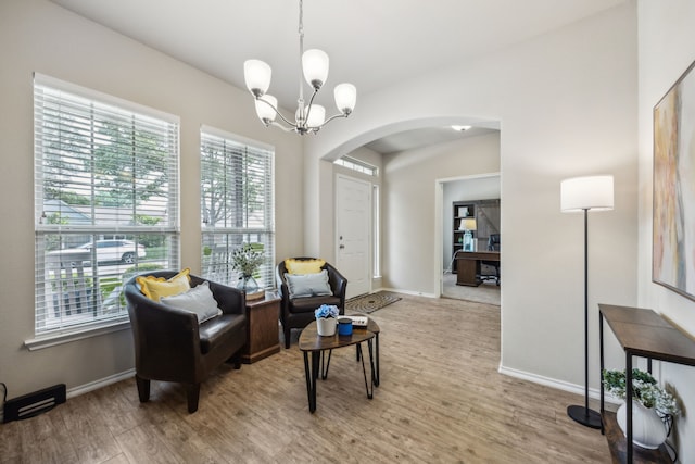 7502 Pacific Dr, Rowlett, TX 75088 - living area with arched walkways, light wood-type flooring, a chandelier, and baseboards