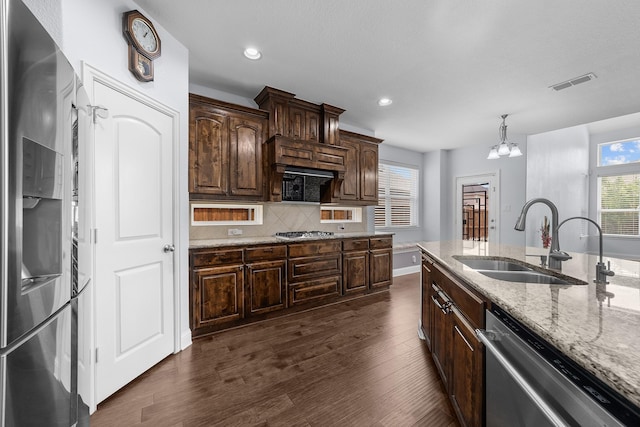 5776 Civetta Ct, Frisco, TX 75035 - kitchen with appliances with stainless steel finishes, a sink, dark wood-type flooring, light stone counters, and decorative backsplash