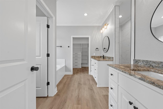 313 Crye Cir, Robinson, TX 76706 - bathroom with wood finished floors, two vanities, recessed lighting, a bath, and a spacious closet