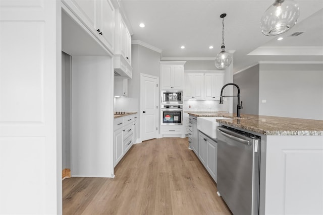 313 Crye Cir, Robinson, TX 76706 - kitchen with appliances with stainless steel finishes, ornamental molding, white cabinetry, light wood-type flooring, and a center island with sink