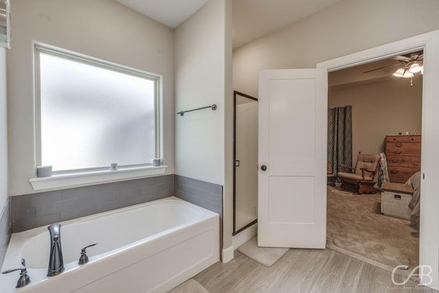 6833 Inverness St, Abilene, TX 79606 - bathroom featuring ceiling fan, a bath, a stall shower, and wood finished floors