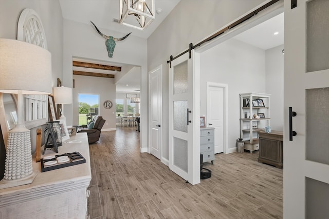 7747 Barber Ranch Rd, Fort Worth, TX 76126 - foyer entrance with a barn door, a chandelier, a high ceiling, light wood-style flooring, and baseboards