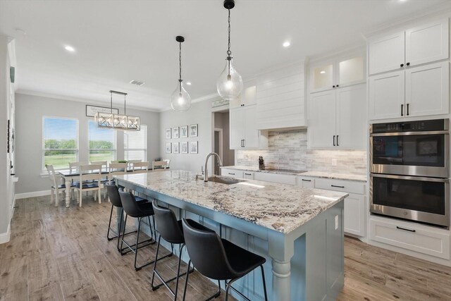 7747 Barber Ranch Rd, Fort Worth, TX 76126 - kitchen with stainless steel double oven, a sink, tasteful backsplash, an island with sink, and crown molding