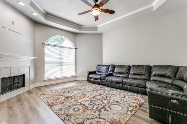7209 Coventry Cir, North Richland Hills, TX 76182 - living room with a tray ceiling, ceiling fan, ornamental molding, wood finished floors, and a tile fireplace