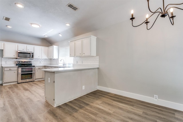 7209 Coventry Cir, North Richland Hills, TX 76182 - kitchen with appliances with stainless steel finishes, lofted ceiling, tasteful backsplash, baseboards, and a peninsula
