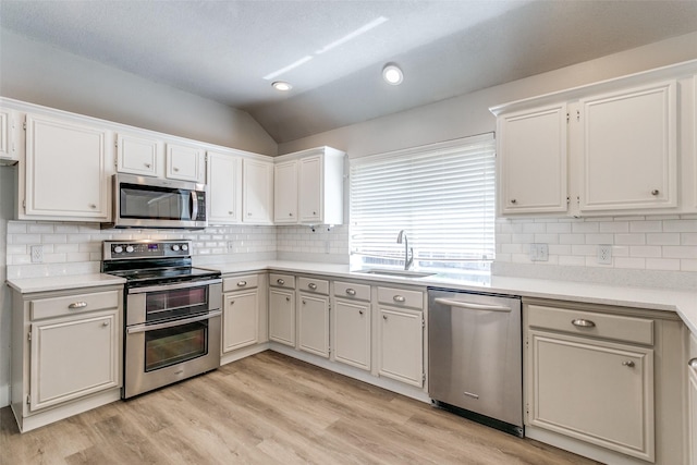 7209 Coventry Cir, North Richland Hills, TX 76182 - kitchen featuring stainless steel appliances, a sink, lofted ceiling, light countertops, and decorative backsplash