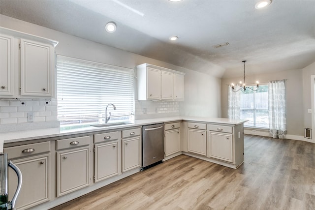 7209 Coventry Cir, North Richland Hills, TX 76182 - kitchen with a sink, stainless steel dishwasher, a peninsula, a chandelier, and light wood-style floors