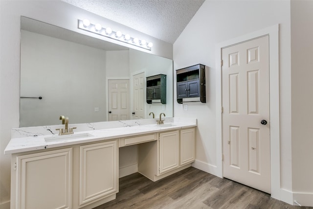 7209 Coventry Cir, North Richland Hills, TX 76182 - full bathroom featuring double vanity, wood finished floors, lofted ceiling, and a textured ceiling
