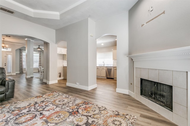 7209 Coventry Cir, North Richland Hills, TX 76182 - living room featuring a fireplace, arched walkways, light wood-style flooring, ceiling fan, and baseboards
