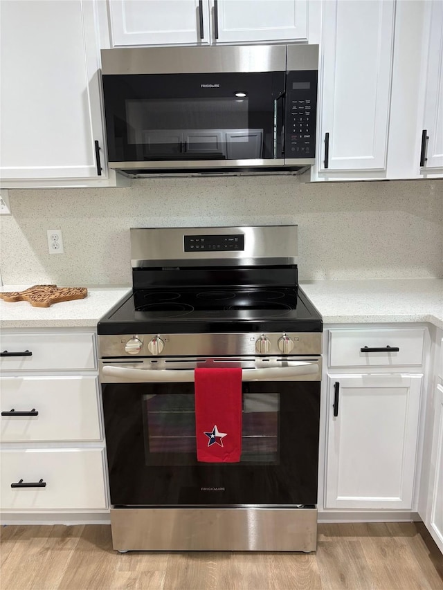3214 51st St, Dallas, TX 75216 - kitchen with appliances with stainless steel finishes, white cabinetry, light wood-type flooring, and light stone counters