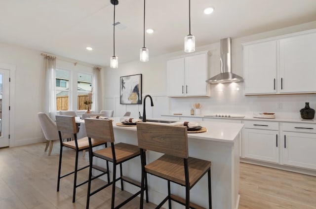 1723 Zachary Ave, Wylie, TX 75098 - kitchen featuring wall chimney exhaust hood, a sink, a center island with sink, light countertops, and light wood-style flooring