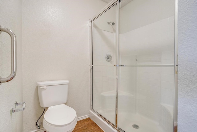 10832 Cobblestone Dr, Benbrook, TX 76126 - bathroom with tiled shower, toilet, wood finished floors, baseboards, and a textured wall
