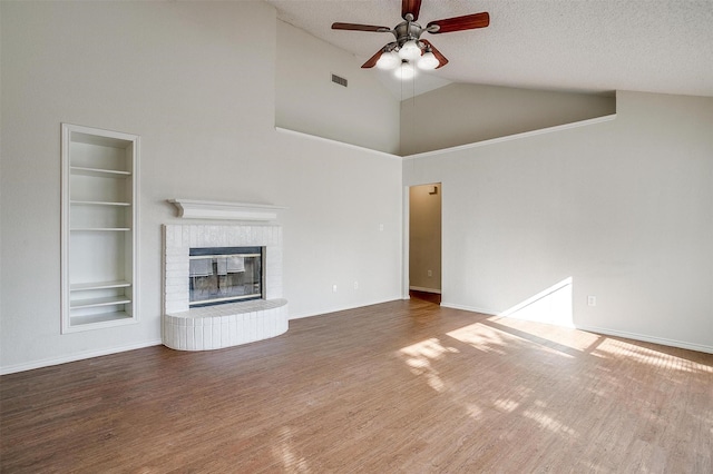 10832 Cobblestone Dr, Benbrook, TX 76126 - unfurnished living room featuring built in shelves, ceiling fan, wood finished floors, a textured ceiling, and a fireplace