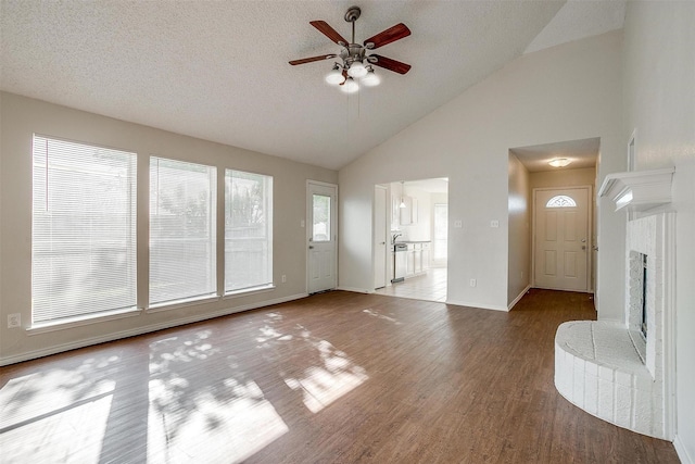 10832 Cobblestone Dr, Benbrook, TX 76126 - unfurnished living room with a ceiling fan, wood finished floors, high vaulted ceiling, a textured ceiling, and baseboards