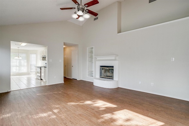 10832 Cobblestone Dr, Benbrook, TX 76126 - unfurnished living room with wood finished floors, ceiling fan, built in shelves, high vaulted ceiling, and baseboards