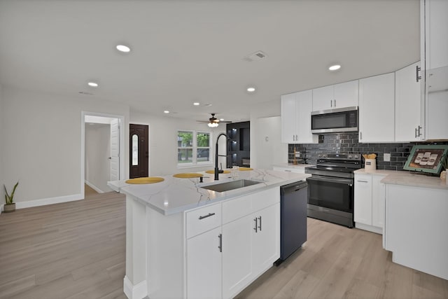 3022 50th St, Dallas, TX 75216 - kitchen featuring stainless steel appliances, a sink, light wood-type flooring, a kitchen island with sink, and recessed lighting