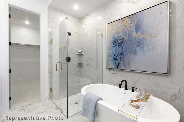 2408 Plumeria Ln, Celina, TX 75009 - bathroom featuring a walk in closet, a marble finish shower, tile walls, a freestanding tub, and marble finish floors