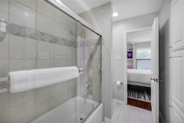 ensuite bathroom featuring enclosed tub / shower combo, baseboards, and recessed lighting