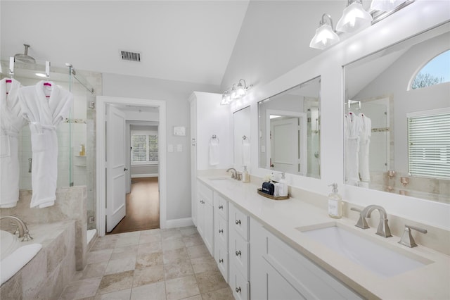 bathroom featuring lofted ceiling, a stall shower, a bath, double vanity, and tile patterned floors