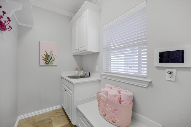 clothes washing area with baseboards, a sink, and ornamental molding