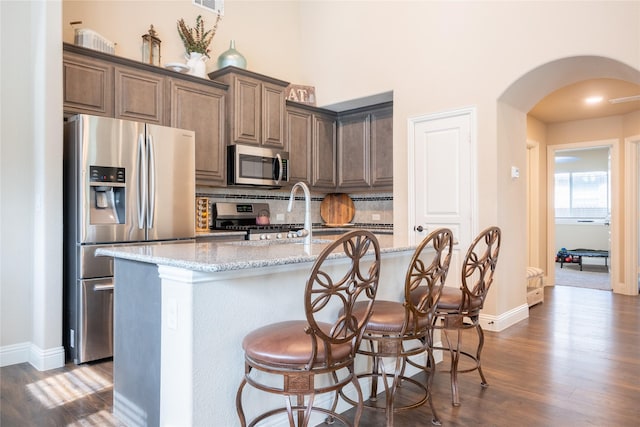 3031 Concourse Dr, Royse City, TX 75189 - kitchen with stainless steel appliances, arched walkways, dark wood-style floors, tasteful backsplash, and baseboards
