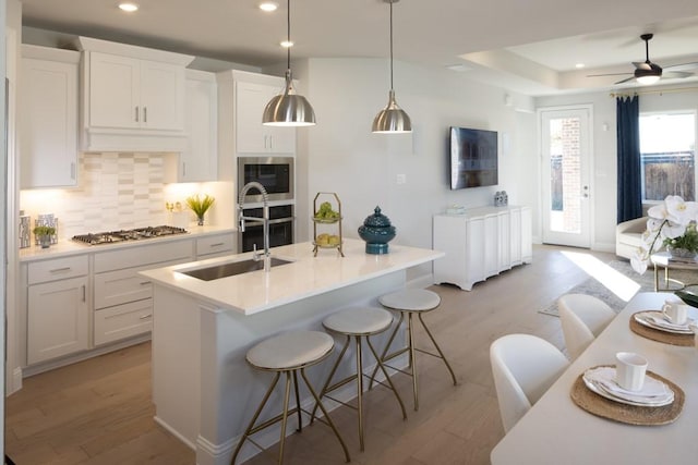 410 Holly Rd, Oak Point, TX 75068 - kitchen featuring appliances with stainless steel finishes, light wood finished floors, backsplash, recessed lighting, and a kitchen breakfast bar