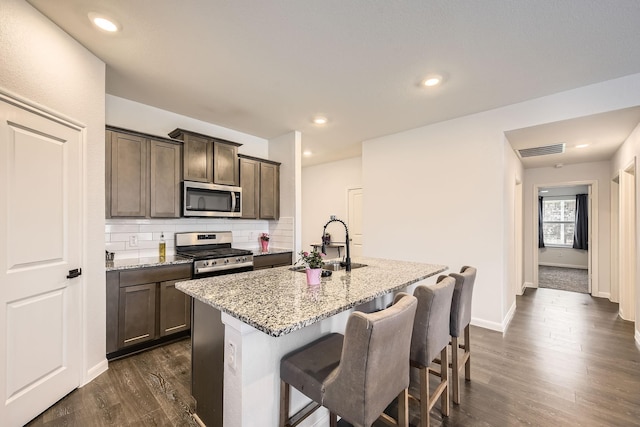 706 Spur Rdg, Princeton, TX 75407 - kitchen with appliances with stainless steel finishes, a sink, light stone counters, a kitchen island with sink, and dark wood-style floors