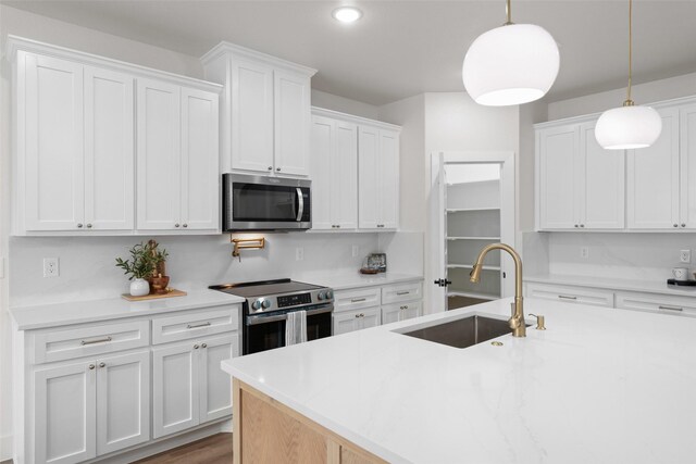 2104 Danner St, Fort Worth, TX 76105 - kitchen with stainless steel appliances, a sink, white cabinetry, light countertops, and hanging light fixtures