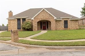 2305 Meadowlark Ln, Bedford, TX 76021 - view of front facade featuring a front yard, stone siding, and a chimney