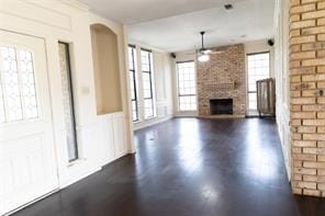 2305 Meadowlark Ln, Bedford, TX 76021 - unfurnished living room featuring a ceiling fan, a large fireplace, dark wood-style floors, and wainscoting