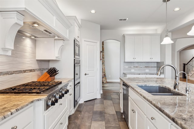 9521 Excursion Dr, Oak Point, TX 75068 - kitchen with arched walkways, appliances with stainless steel finishes, a sink, white cabinets, and recessed lighting