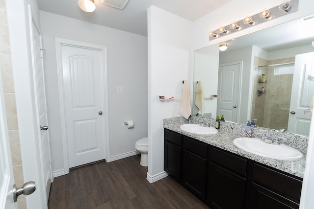 1402 Fantail Ln, Ennis, TX 75119 - bathroom featuring double vanity, wood finished floors, a tile shower, toilet, and baseboards
