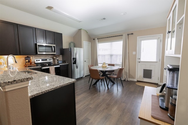1402 Fantail Ln, Ennis, TX 75119 - kitchen featuring appliances with stainless steel finishes, a sink, light stone counters, lofted ceiling, and tasteful backsplash