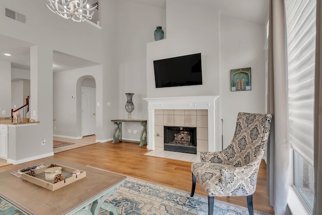 6813 Andress Dr, Fort Worth, TX 76132 - living room featuring wood finished floors, arched walkways, a chandelier, a tile fireplace, and baseboards