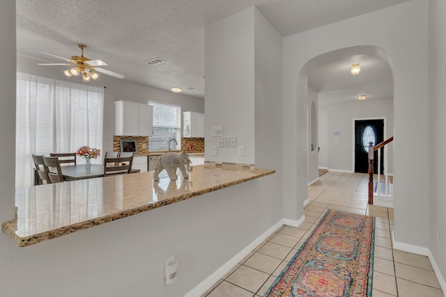 6813 Andress Dr, Fort Worth, TX 76132 - kitchen featuring a ceiling fan, arched walkways, a peninsula, light tile patterned flooring, and white cabinets