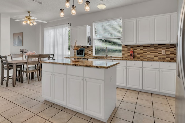 6813 Andress Dr, Fort Worth, TX 76132 - kitchen with decorative backsplash, a sink, light tile patterned floors, a kitchen island, and white cabinets