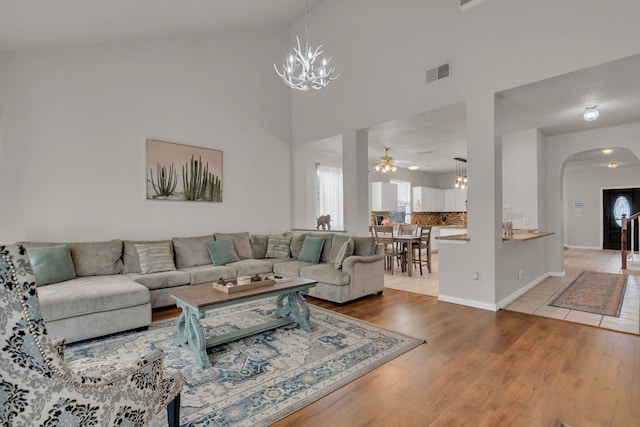 6813 Andress Dr, Fort Worth, TX 76132 - living room featuring a chandelier, arched walkways, light wood-type flooring, ceiling fan, and high vaulted ceiling