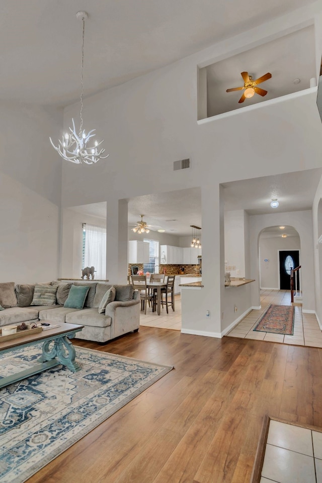 6813 Andress Dr, Fort Worth, TX 76132 - living area featuring a chandelier, a ceiling fan, arched walkways, wood finished floors, and a high ceiling